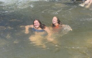 two girls in a river laughing